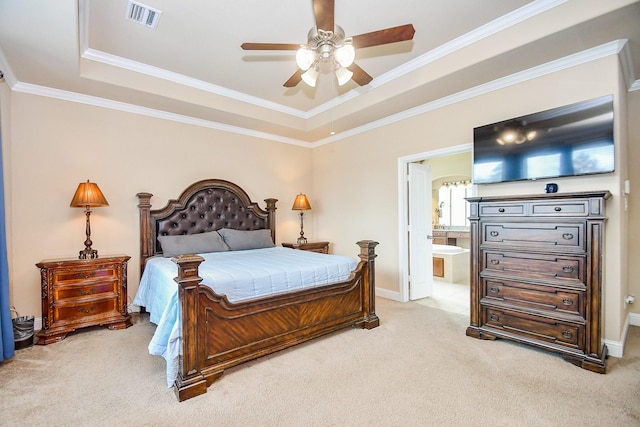 carpeted bedroom featuring ceiling fan, crown molding, a tray ceiling, and ensuite bath