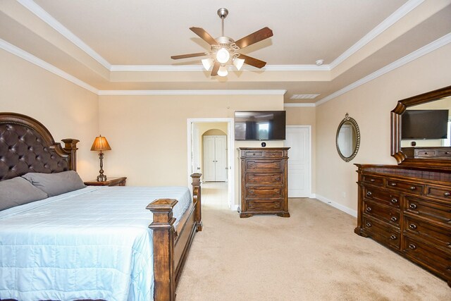 carpeted bedroom with ceiling fan, a raised ceiling, and ornamental molding