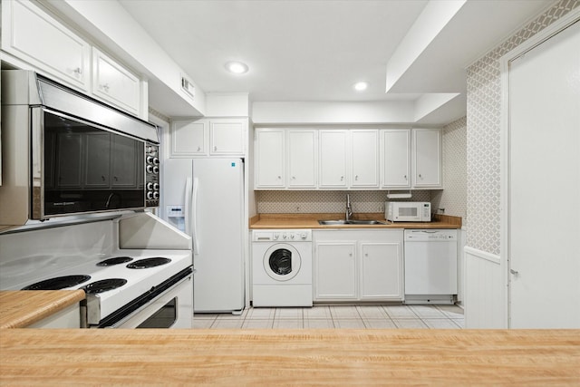 kitchen featuring sink, wood counters, white appliances, washer / dryer, and white cabinets