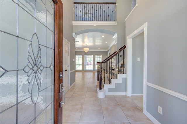 entryway featuring a towering ceiling, light tile patterned flooring, and ornamental molding