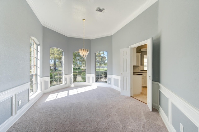 unfurnished dining area featuring light carpet, a chandelier, and ornamental molding