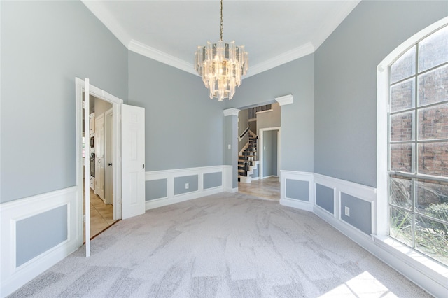 carpeted spare room with a notable chandelier and ornamental molding