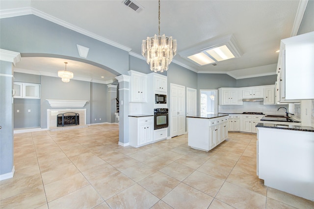 kitchen featuring a tile fireplace, white cabinetry, a center island, decorative light fixtures, and black appliances