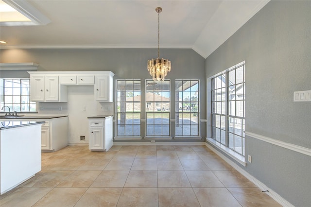 kitchen with lofted ceiling, an inviting chandelier, white cabinets, sink, and hanging light fixtures