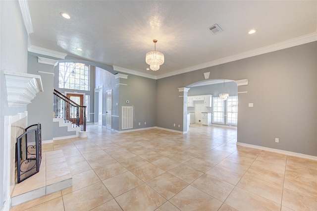 interior space featuring light tile patterned floors, a textured ceiling, an inviting chandelier, and crown molding