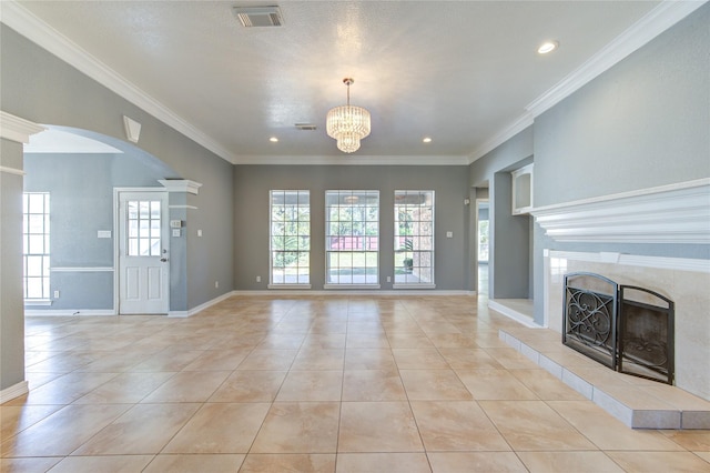 unfurnished living room with a tile fireplace, light tile patterned floors, a chandelier, and ornamental molding