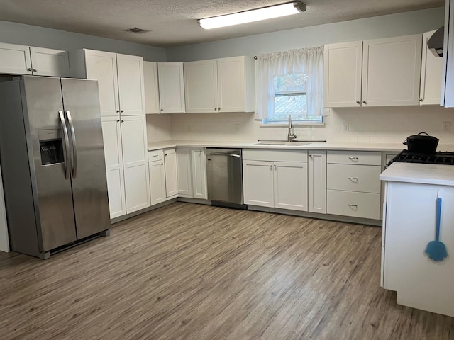 kitchen with white cabinets, light hardwood / wood-style floors, sink, and stainless steel appliances