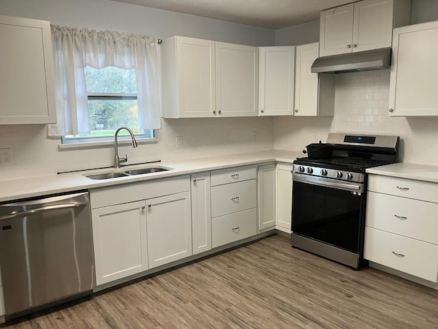 kitchen with white cabinetry, sink, backsplash, appliances with stainless steel finishes, and light wood-type flooring