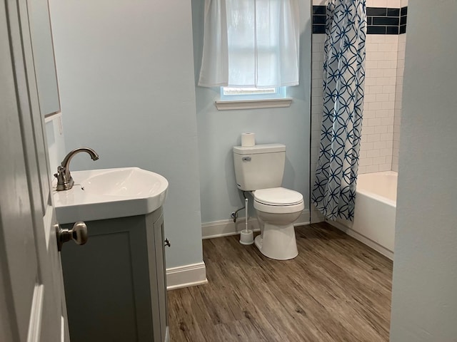 full bathroom featuring shower / bath combo with shower curtain, hardwood / wood-style floors, vanity, and toilet