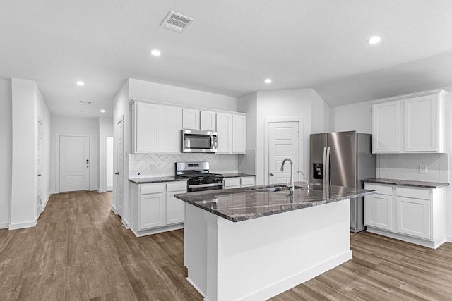 kitchen featuring stainless steel appliances, white cabinetry, a center island with sink, and sink