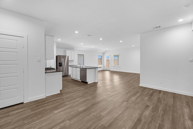 kitchen featuring light hardwood / wood-style flooring, decorative backsplash, appliances with stainless steel finishes, a kitchen island, and white cabinetry