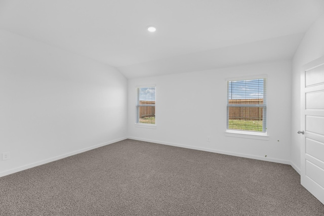 carpeted spare room featuring a healthy amount of sunlight and lofted ceiling