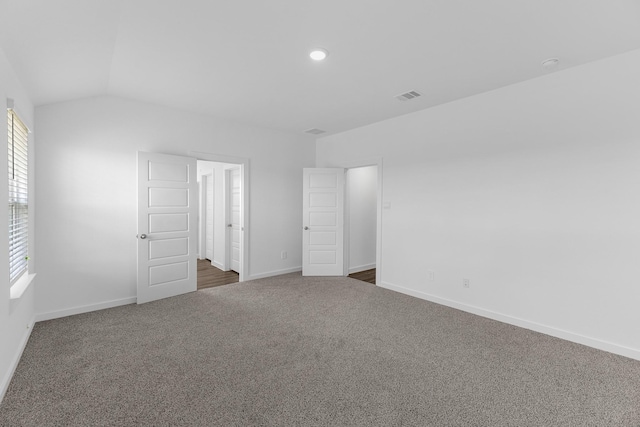 spare room with dark carpet and lofted ceiling