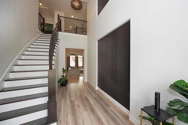 entryway featuring a towering ceiling and light wood-type flooring