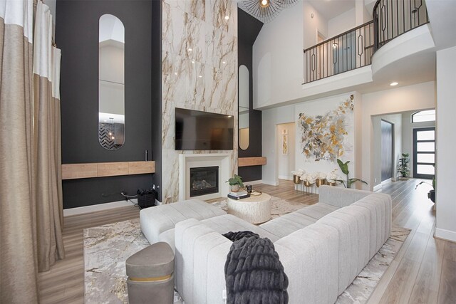 living room featuring a fireplace, a towering ceiling, and light hardwood / wood-style floors