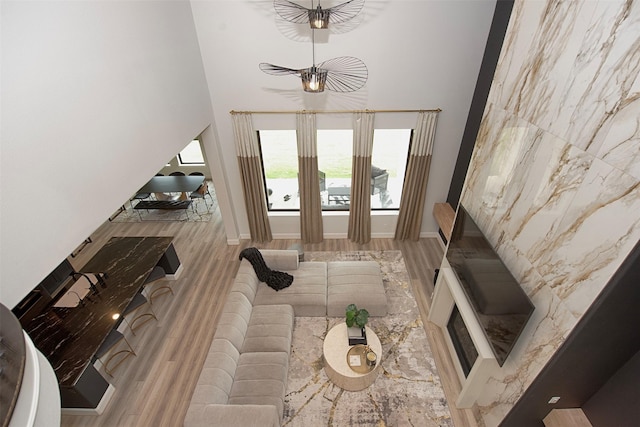 living room with an inviting chandelier, a towering ceiling, and light hardwood / wood-style flooring