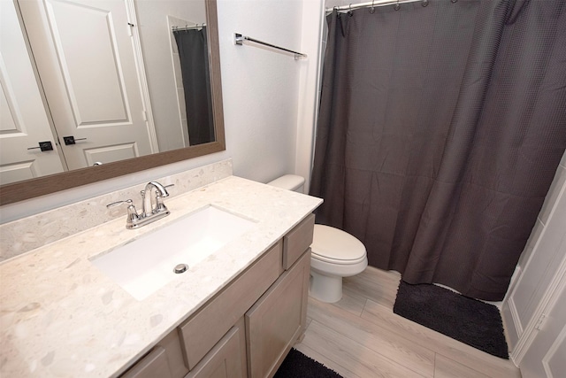 bathroom with wood-type flooring, vanity, toilet, and walk in shower