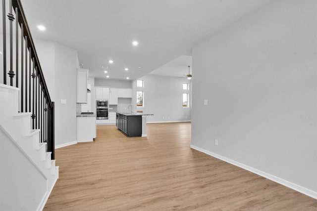 kitchen with white cabinetry, ceiling fan, sink, a kitchen bar, and a center island with sink