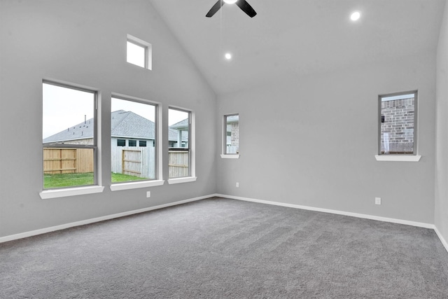 carpeted spare room with ceiling fan, plenty of natural light, and high vaulted ceiling