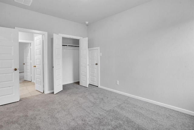 unfurnished bedroom with light colored carpet and a closet