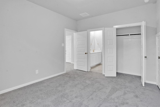 unfurnished bedroom featuring connected bathroom, a closet, and light colored carpet