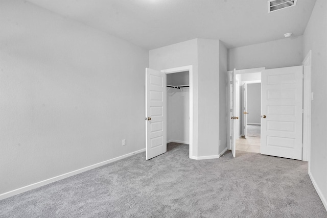 unfurnished bedroom with light colored carpet and a closet