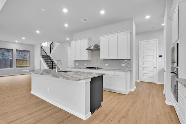 kitchen with a kitchen island with sink, sink, white cabinets, and appliances with stainless steel finishes