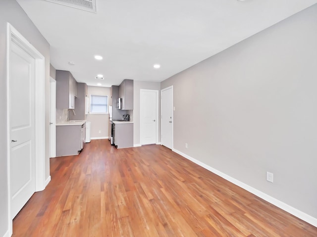 unfurnished living room featuring light wood-type flooring and sink