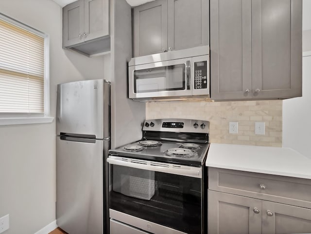 kitchen featuring tasteful backsplash, gray cabinets, and stainless steel appliances