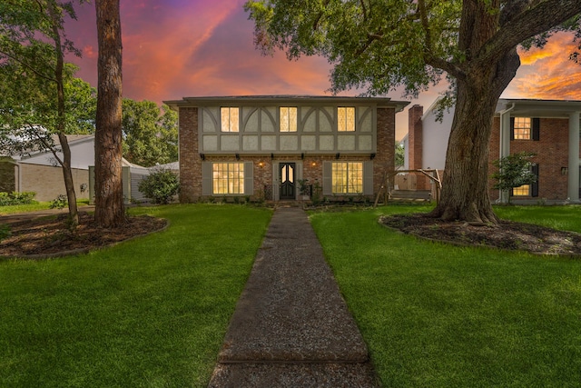 english style home featuring a lawn