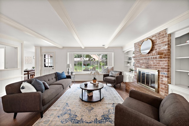 living room with a brick fireplace, ornamental molding, hardwood / wood-style flooring, built in features, and beamed ceiling