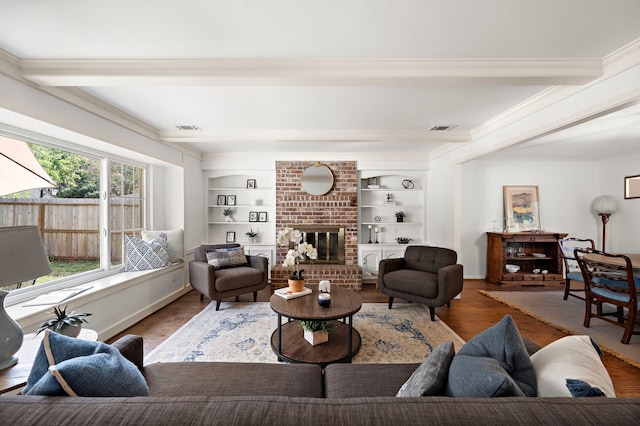 living room with a fireplace, hardwood / wood-style floors, built in features, and crown molding