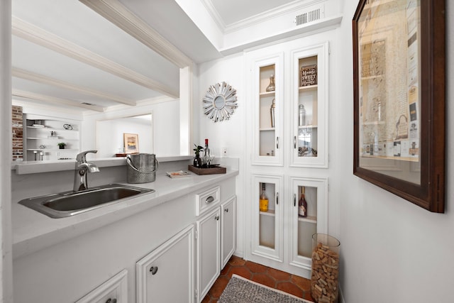 bar with built in shelves, white cabinetry, ornamental molding, and sink