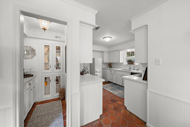 kitchen featuring white cabinetry, sink, white fridge, and crown molding