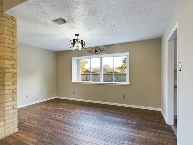 unfurnished dining area with dark hardwood / wood-style flooring, a textured ceiling, and an inviting chandelier