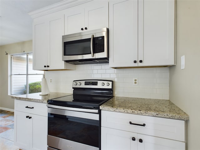 kitchen with light stone countertops, tasteful backsplash, light tile patterned flooring, white cabinets, and appliances with stainless steel finishes