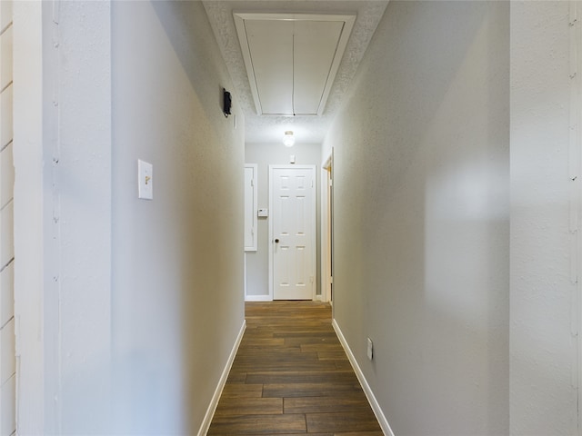 hall with a textured ceiling and dark wood-type flooring