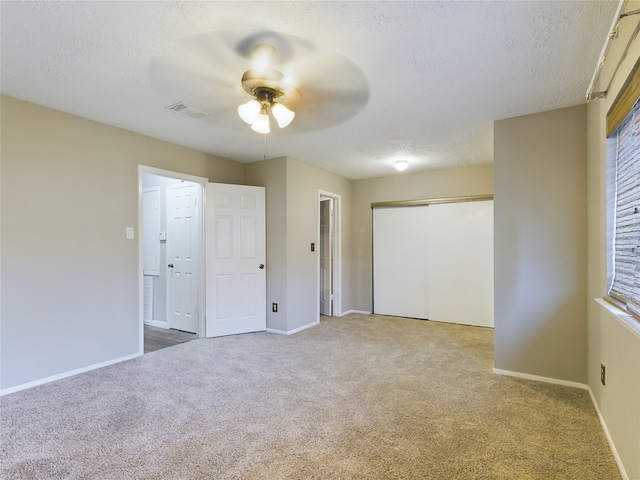 unfurnished bedroom featuring carpet, a textured ceiling, and ceiling fan