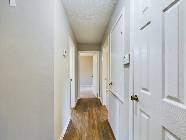 corridor with dark wood-type flooring and a textured ceiling