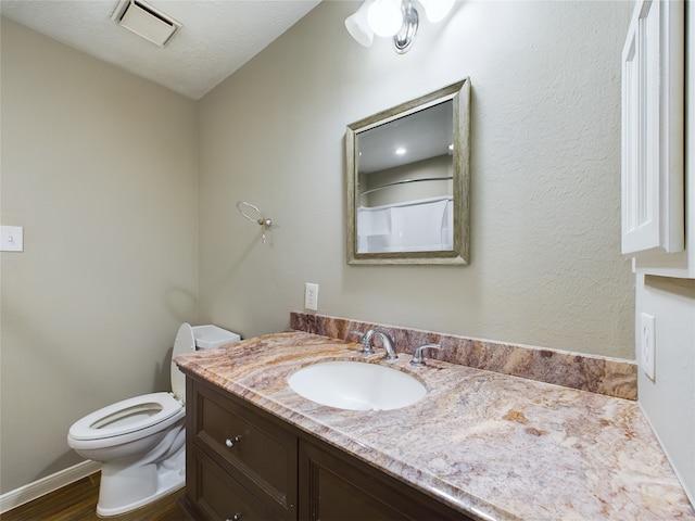 bathroom with vanity, toilet, wood-type flooring, and a textured ceiling