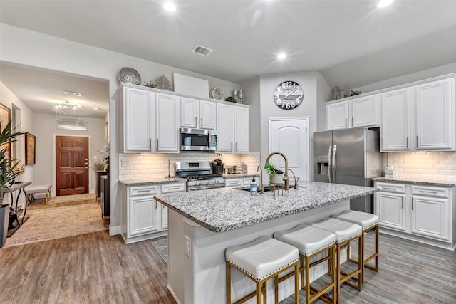 kitchen featuring white cabinets, stainless steel appliances, and a kitchen island with sink