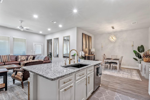 kitchen with white cabinets, a center island with sink, light hardwood / wood-style flooring, and sink