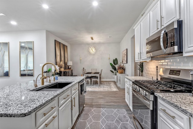 kitchen with stainless steel appliances, sink, white cabinets, dark hardwood / wood-style floors, and an island with sink