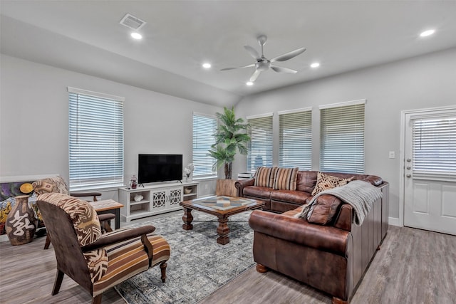 living room featuring ceiling fan, light hardwood / wood-style floors, and vaulted ceiling