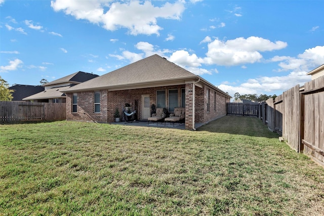 rear view of property featuring a yard and a patio area