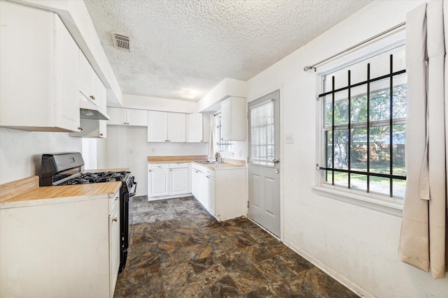 kitchen with black range with gas stovetop, white cabinets, and a textured ceiling