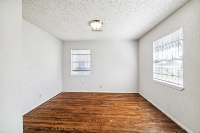 unfurnished room featuring a textured ceiling and dark hardwood / wood-style floors