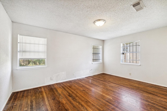 spare room with a textured ceiling and dark hardwood / wood-style floors