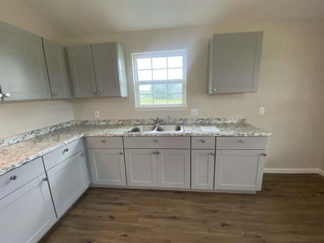 kitchen featuring dark hardwood / wood-style floors, light stone counters, and sink