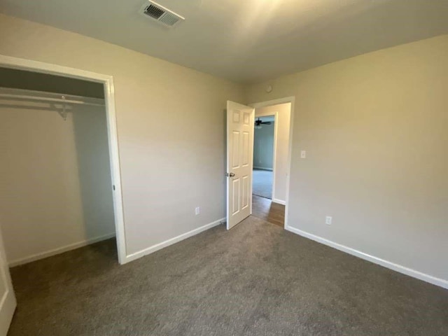 unfurnished bedroom featuring a closet and dark colored carpet